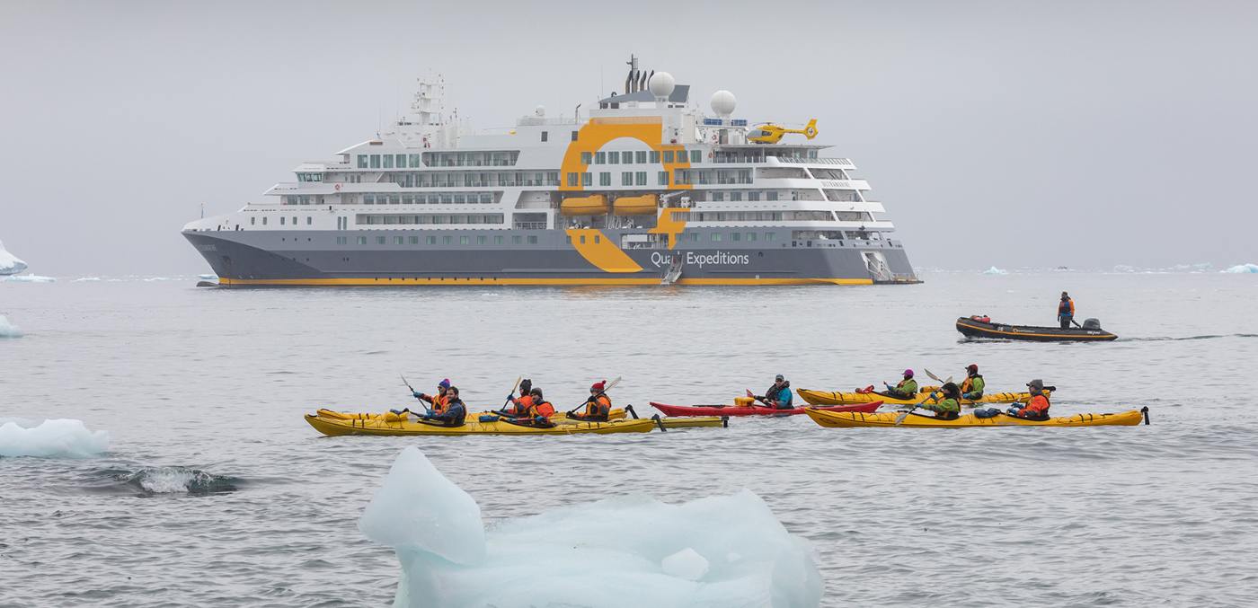 people in kayak on water in front of ship