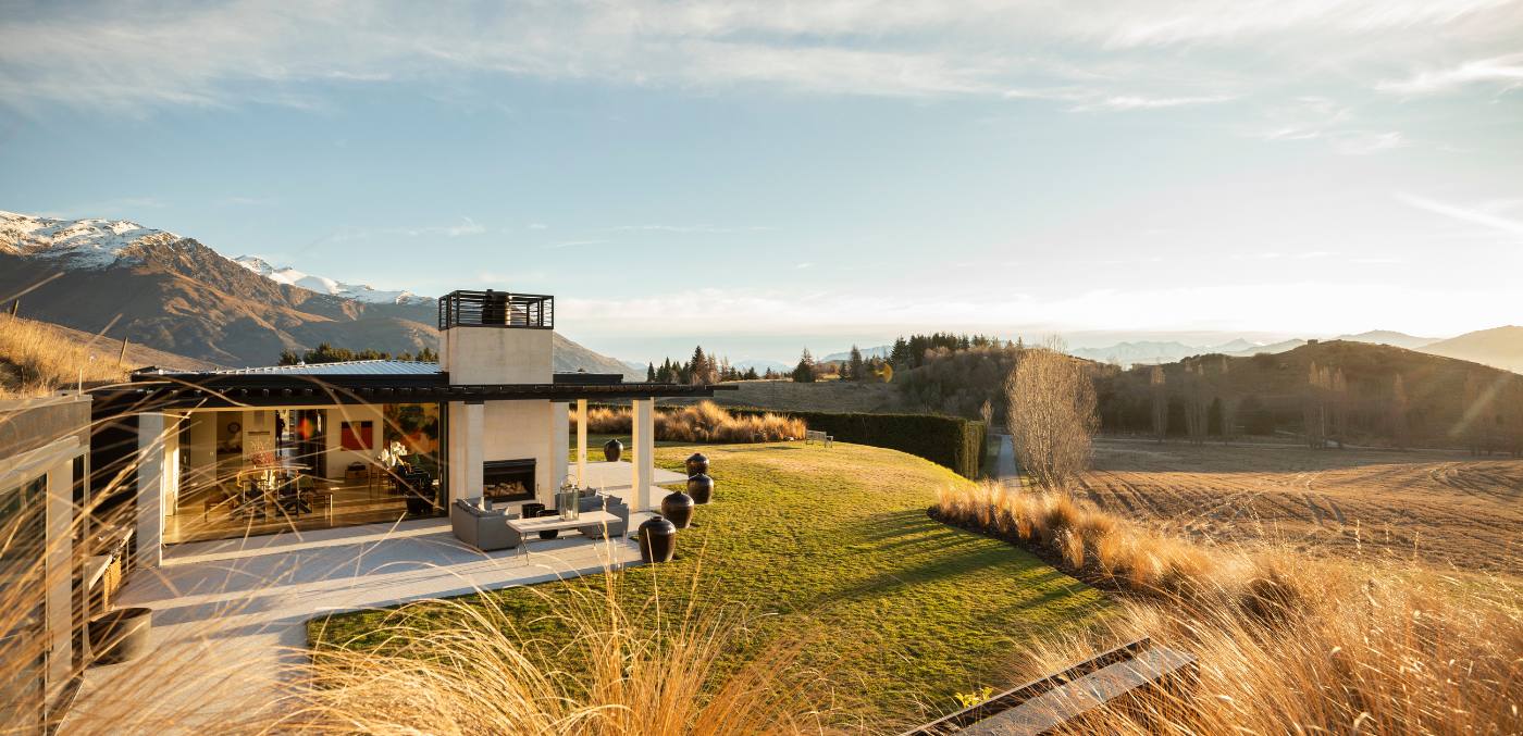 house on top of a grassy hill overlooking a field