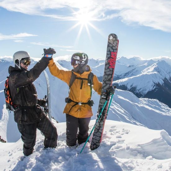 Skiiers high-fiving while heli-ski with Minaret